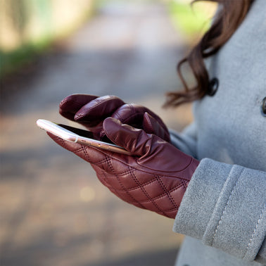 woman wearing touchscreen leather quilted gloves