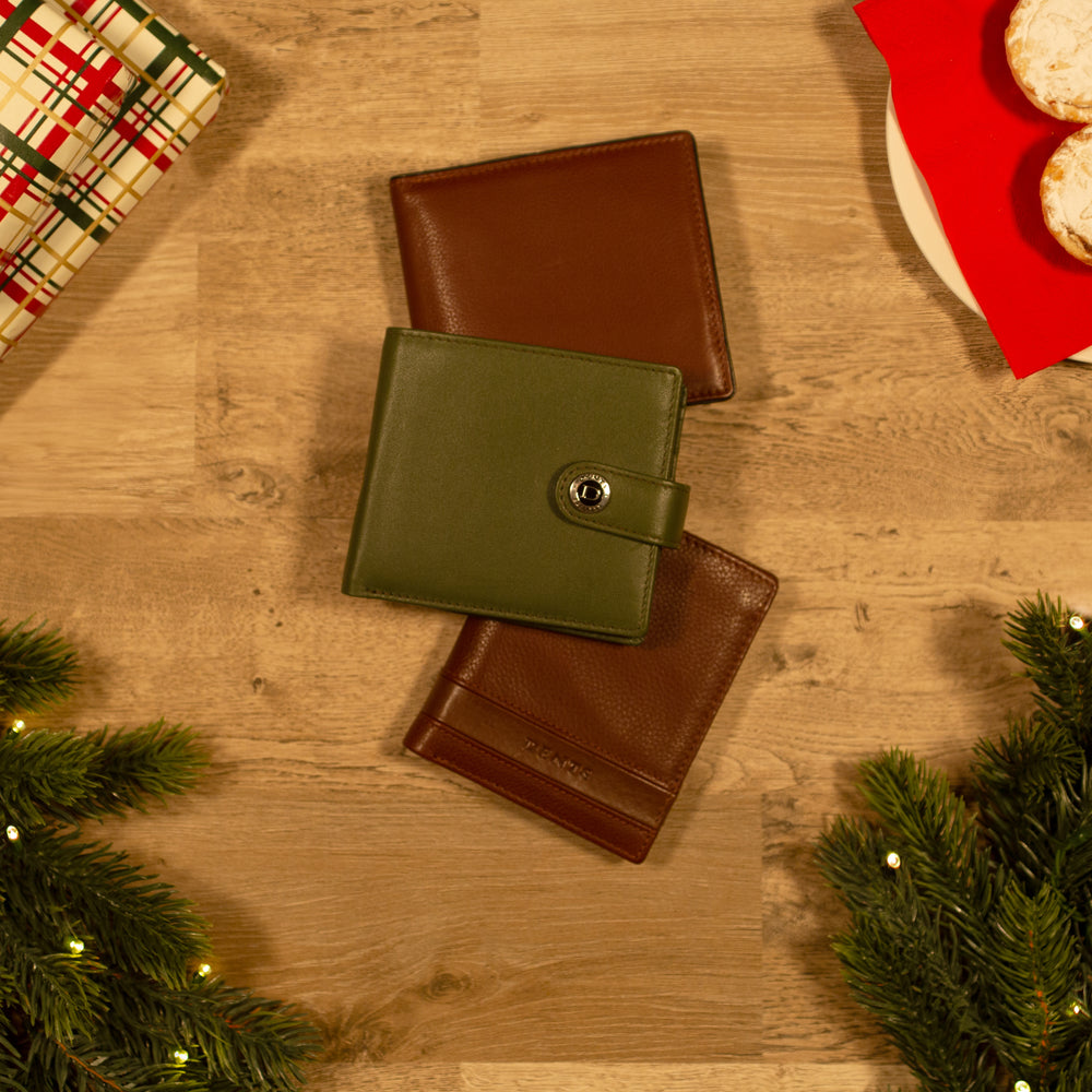 Selection of green and brown men's leather wallets on a wooden table with Christmas accessories