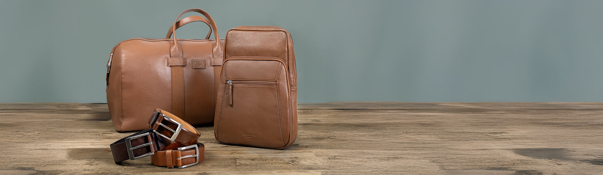 A set of men's bags and belts in brown colours on wooden and grey background 