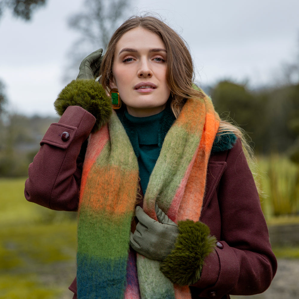 Woman wearing green gloves and a blanket scarf in the countryside