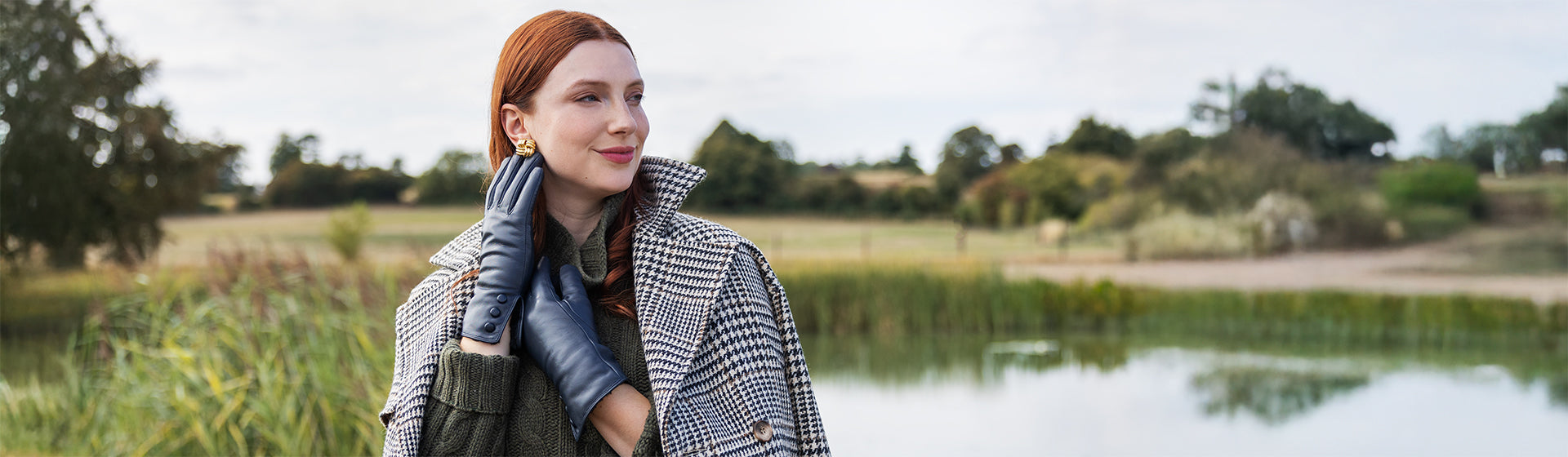 Woman wearing leather gloves with three buttons in navy walking around a meadow