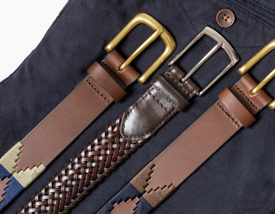 Collection of leather belts with various buckles on a dark fabric background