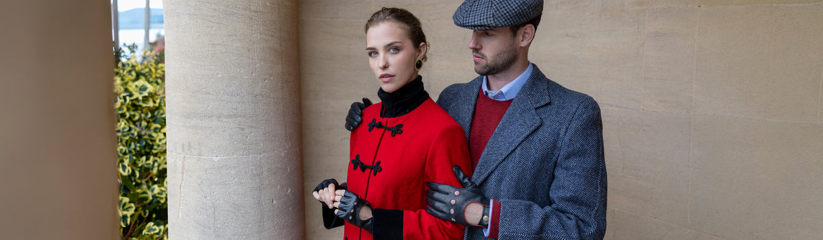 A man and a woman wearing leather driving gloves in black outdoors