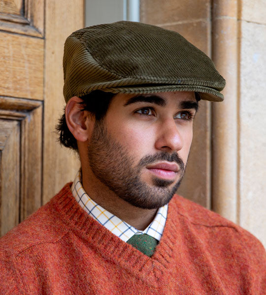 Man wearing corduroy flat cap in olive whilst at a state home