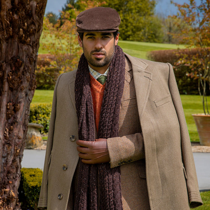 Man wearing chocolate cable knit scarf with marl yarn in a park