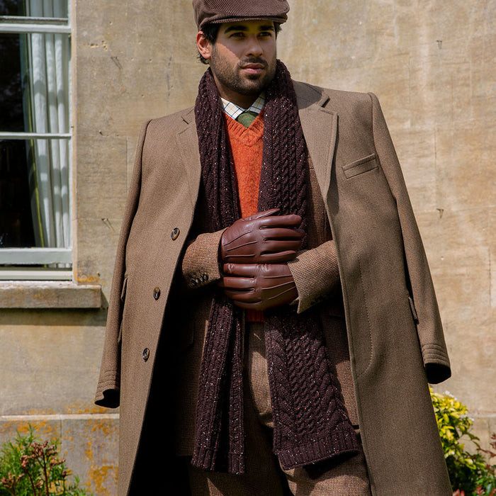 Man wearing chocolate cable knit scarf with marl yarn in a park