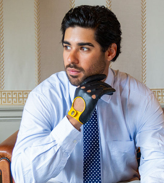Man wearing a white shirt and blue tie wearing black and yellow gloves.