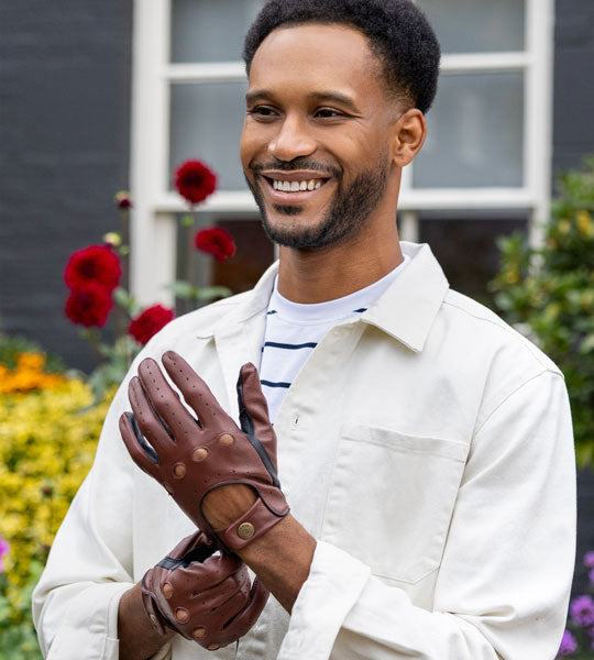 Man wearing touchscreen two-colour leather driving gloves in brown and black in the garden. 