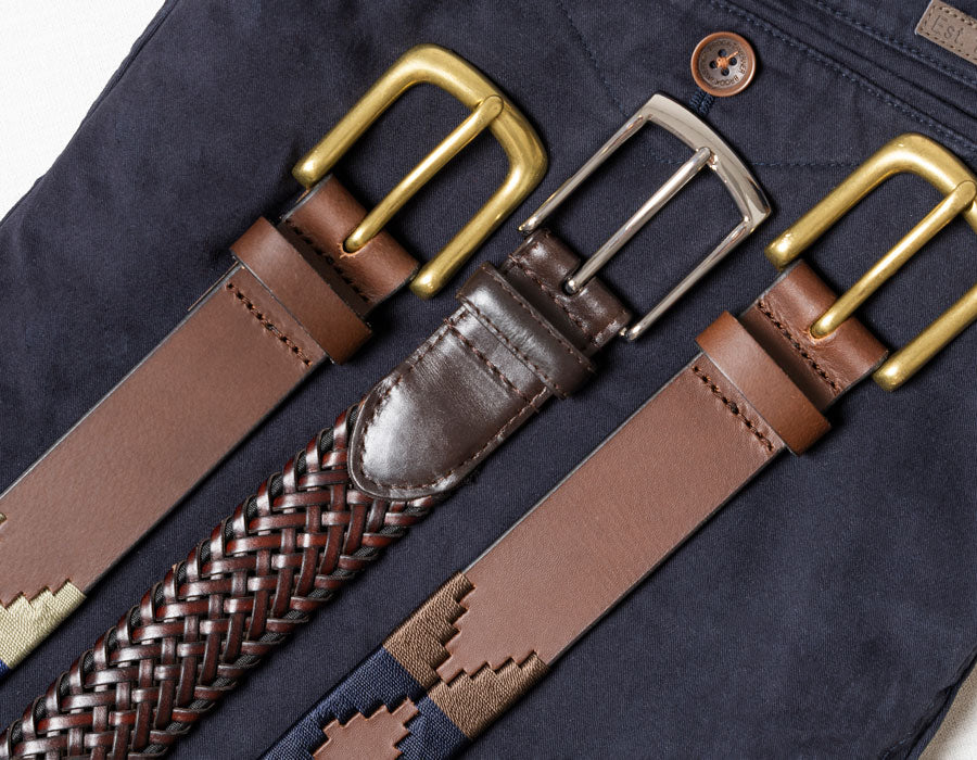 Various men's belts in brown, blue and navy on navy chinos. 