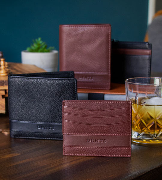 Men's leather wallets in various colours and styles standing on a wooden table