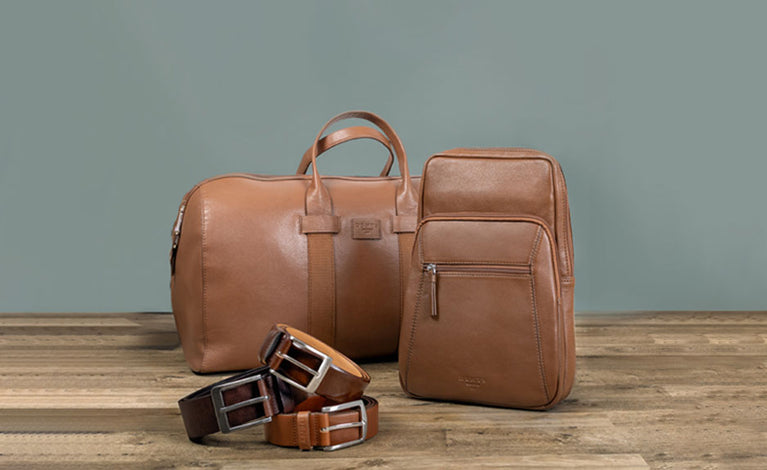 A set of men's bags and belts in brown colours on wooden and grey background 