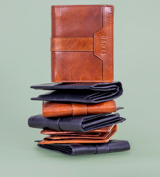 Men's leather wallets in various colours in a stack on a green background