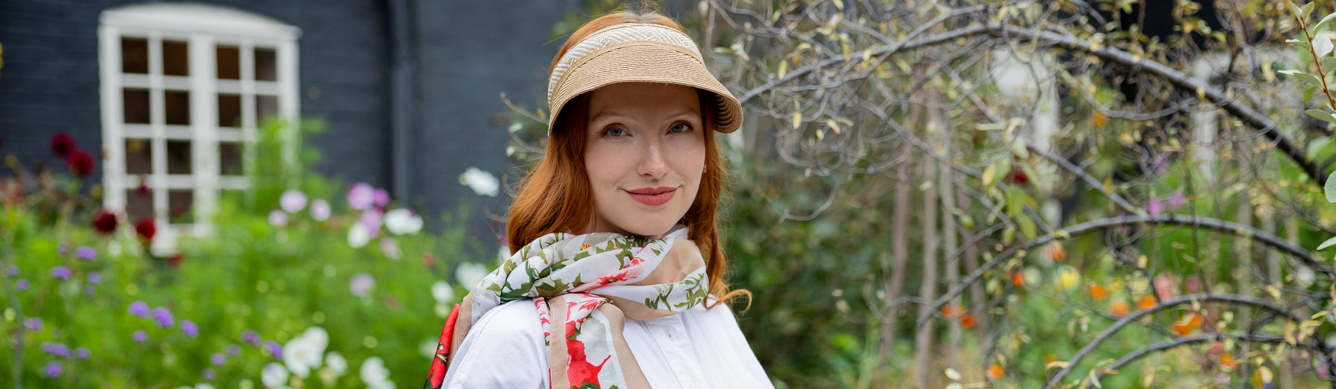 Woman in a garden wearing a hat and scarf