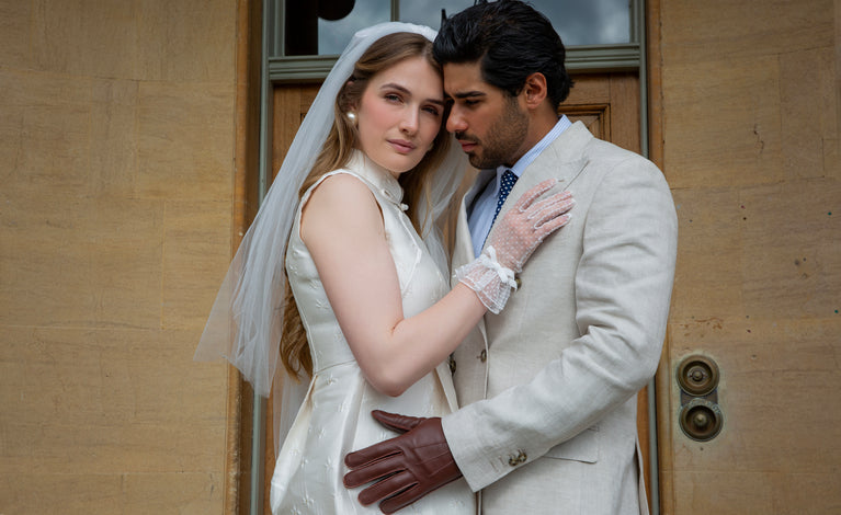 Man and woman getting married wearing spotty tulle gloves with double cuff and decorative bow in white.