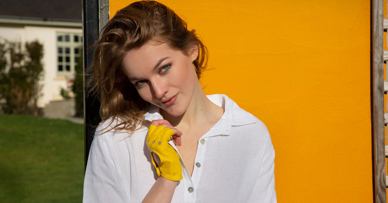 Woman wearing fingerless leather driving gloves in yellow on holiday