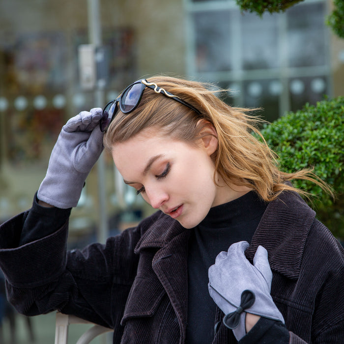 woman wearing touchscreen faux suede gloves with bow in grey whilst out for walk