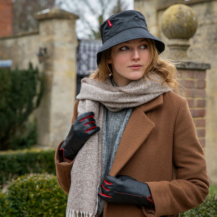 Woman wearing leather gloves, scarf and bucket hat at a country estate