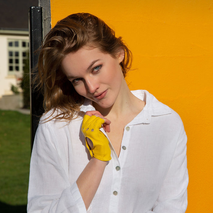 Woman wearing yellow fingerless leather gloves and a white shirt on holiday