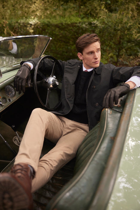 Man wearing mens black three point leather driving gloves in a car in the forest